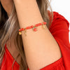 Bracciale Corallino indossato al polso, con perline corallo e beige, pendenti marini dorati e granchio rosso.