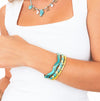 Bracciale Oceania in acciaio inossidabile color oro con decorazione smaltata ispirata alle onde del mare, fotografato su sfondo bianco.