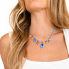 Dettaglio dei charm della Collana Maiolica, con fiori bianchi e blu, sole, palma e cuore dorati.