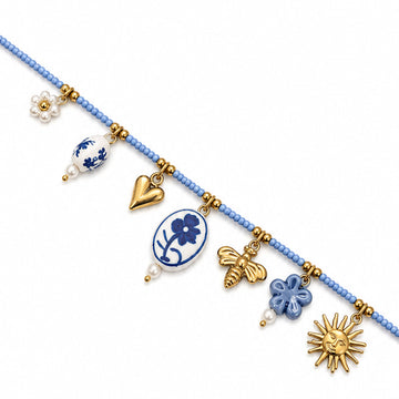 Collana Maiolica Acheta Jewels su fondo bianco, con perline azzurre, pendente floreale bianco e blu e charm dorati.