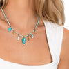 Collana con perline turchesi e ciondoli marini indossata al collo, dettaglio del pesciolino centrale.